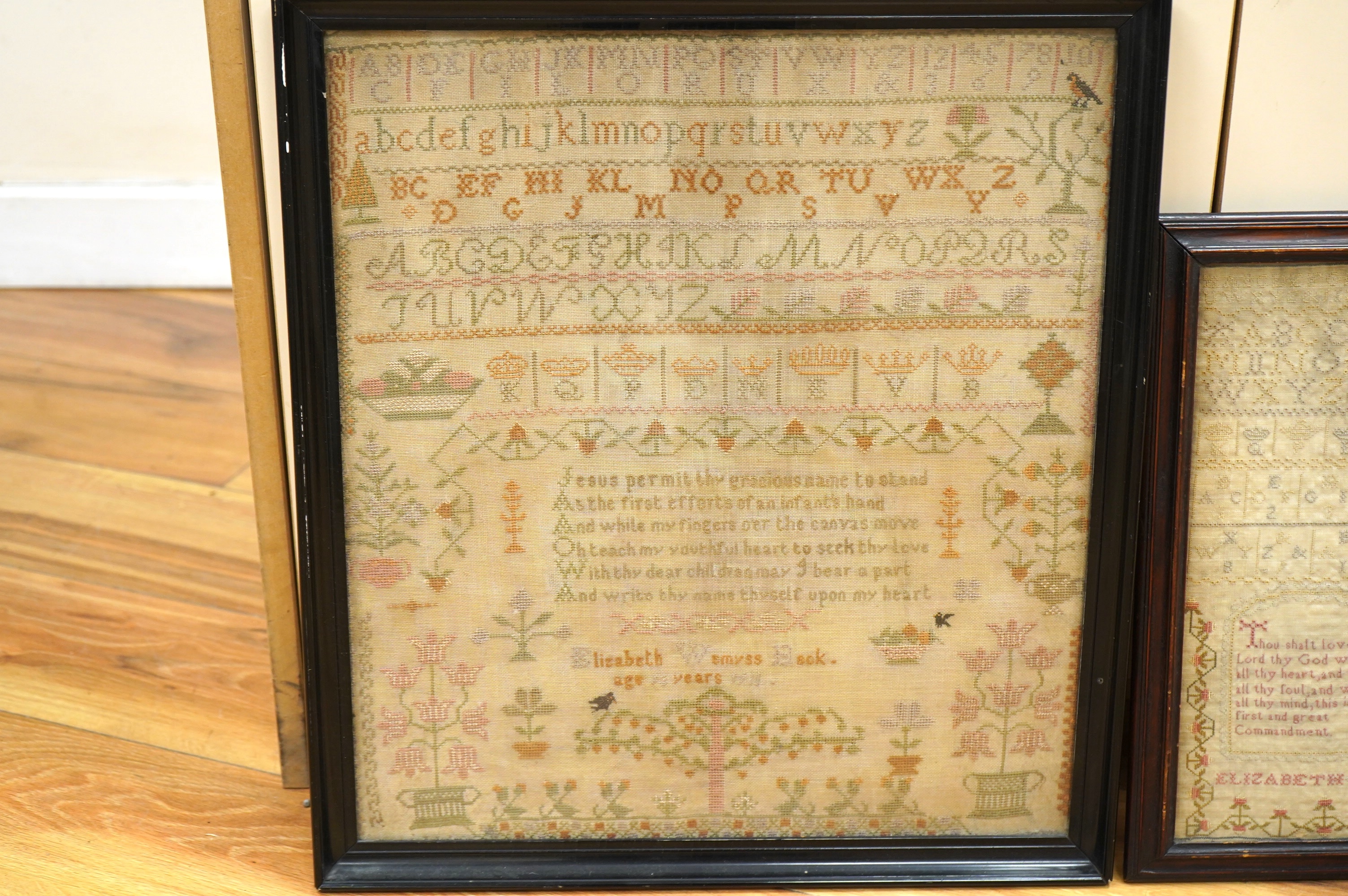 Two samplers; one late 18th century, the other early 20th century, the 18th century sampler by Elizabeth Chamberlain dated 1777, worked with an alphabet and framed verse bordered with vineous flowers, the later sampler b